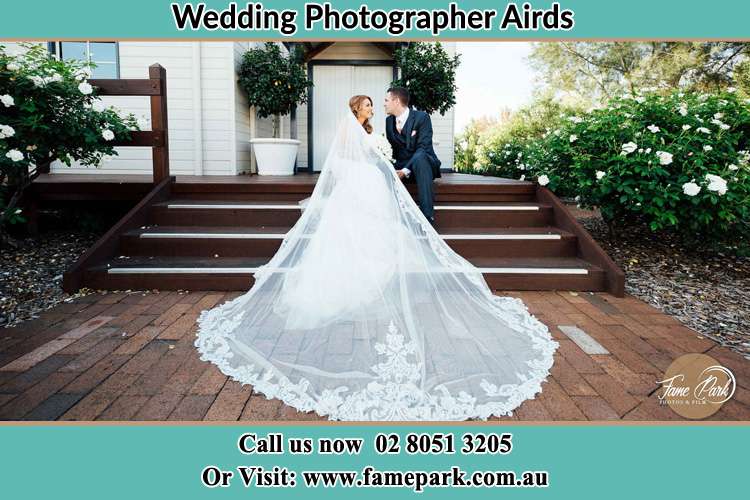 Photo of the Bride and the Groom looking each other while sitting at the staircase Airds NSW 2560