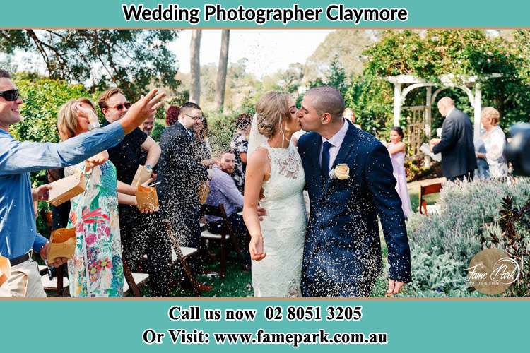 Photo of the Bride and the Groom kissing while showering rice by the visitors Claymore NSW 2559