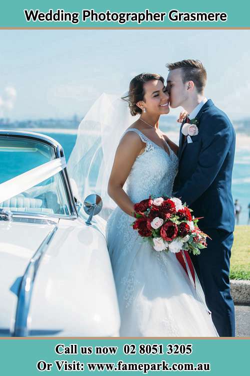 Photo of the Groom kiss the Bride besides the bridal car Grasmere NSW 2570