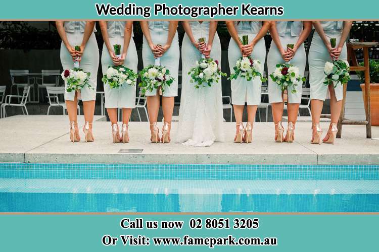 Behind photo of the Bride and the bridesmaids holding flowers near the pool Kearns NSW 2558