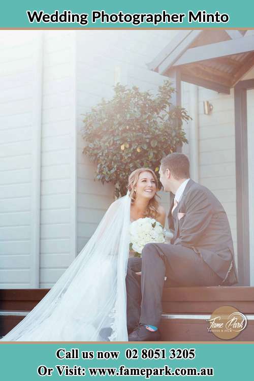 Photo of the Bride and the Groom looking each other while sitting at the staircase Minto NSW 2566