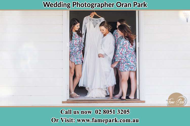 Photo of the Bride and the bridesmaids checking the wedding gown at the front door Oran Park NSW 2570