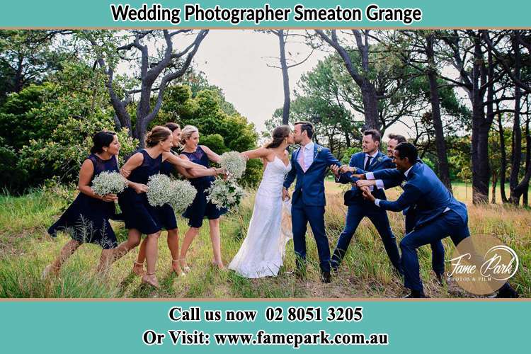 Photo of the Bride and the Groom kissing while teasing by the entourage Smeaton Grange NSW 2567